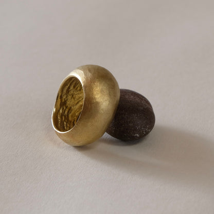 A  gold ring with a unique rounded, egg-like shape, A large hand carved gold ring .