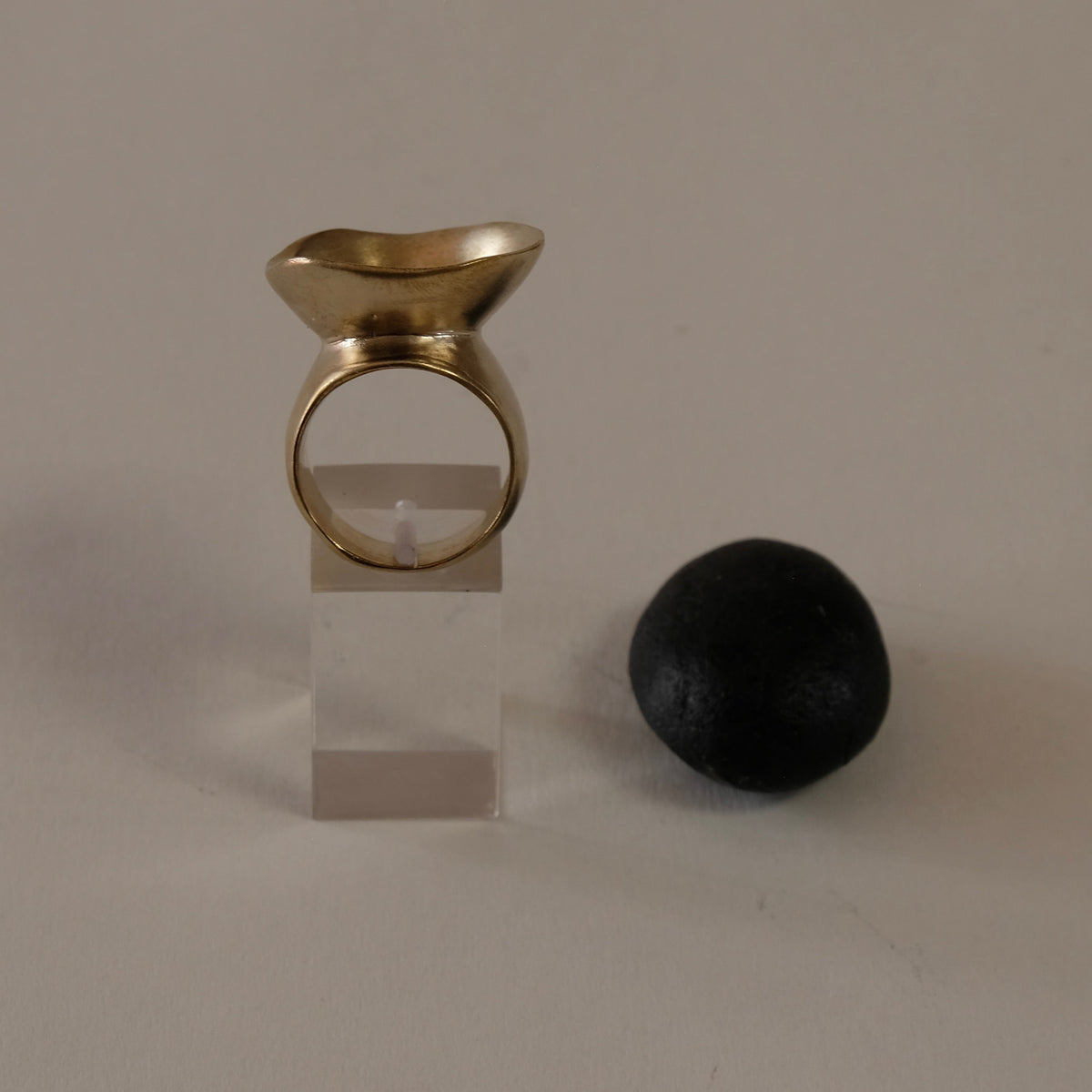 A gold ring with a sculptural, curved top resembling a small  wave, 